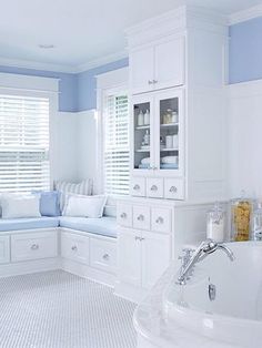 a large white bathroom with blue walls and furniture in the bathtub, window seat