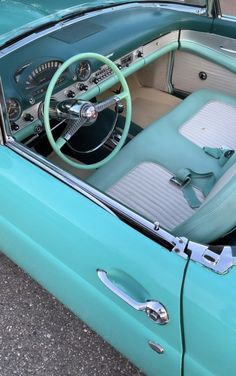 the interior of an old car is turquoise with white trim and dash board, along with steering wheel