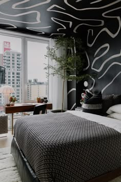 a black and white bedroom with a large window overlooking the cityscape is pictured in this image