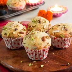 several muffins on a wooden plate with candles in the background