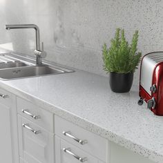 a red toaster sitting on top of a kitchen counter next to a potted plant