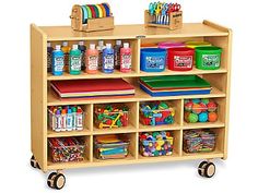 a child's wooden toy storage unit with lots of toys on wheels and bins