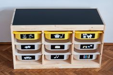 a toy storage unit with yellow bins and black top on wooden floored floor