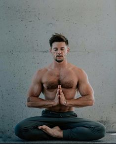 a shirtless man sitting in the middle of a yoga pose with his hands together