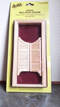 an open wooden door with shutters on the outside in a cardboard box, sitting on a table