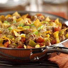 a skillet filled with nachos on top of a wooden table