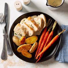 a black plate topped with chicken, potatoes and carrots