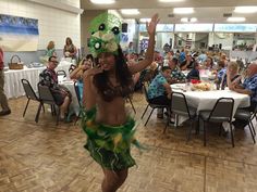 a woman in a hula skirt dancing on the dance floor with other people watching