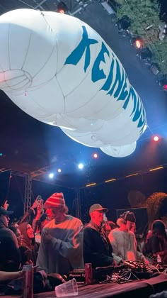 a group of people sitting on top of a stage under a large white balloon in the air