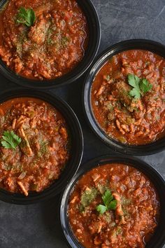 three black bowls filled with different types of food and garnished with parsley