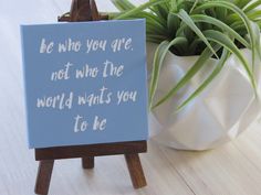 a blue sign sitting on top of a wooden easel next to a potted plant