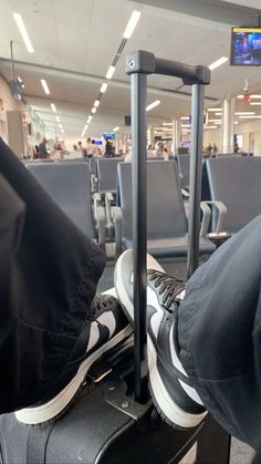 a person sitting in an airport with their feet propped up on the handlebars