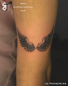 an arm tattoo with two wings on the back of someone's left leg,