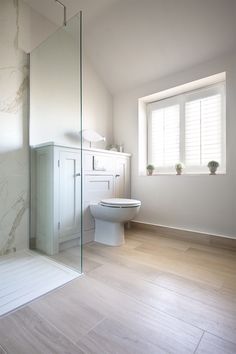 a bathroom with a toilet, sink and shower in it's center wall next to a window