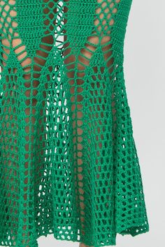 a woman wearing a green crochet skirt with cutouts on the bottom and sides