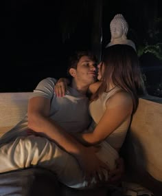 a man and woman sitting on a couch in the dark with their arms around each other