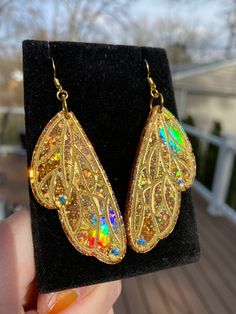 These gorgeous one of a kind  butterfly/fairy wing earrings are handmade with resin and are very lightweight. They are iridescent and holographic and will be sure to make a statement on your ears 💖 Handmade by Katie  KG Design & Decor Please follow my on social media  Instagram: @KG_DesignandDecor Facebook: KG Design and Decor Please be aware that this is handmade art and perfection has no place in art.  However, this was crafted with love and intention and I hope you are satisfied with your pu Iridescent Fairy Style Jewelry For Party, Iridescent Fantasy Jewelry For Parties, Gold Fantasy Earrings For Party, Iridescent Fairy Jewelry For Parties, Handmade Fairy Earrings For Party, Gold Fairy Style Handmade Earrings, Handmade Wing-shaped Jewelry For Party, Iridescent Fairy-style Jewelry For Parties, Gold Fairy Earrings For Gift