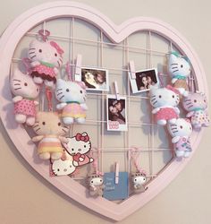 a heart shaped wall hanging with hello kitty stuffed animals and photos attached to the hooks