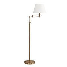 a floor lamp with a white shade on the base and a gold metal pole,