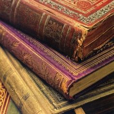 three old books are stacked on top of each other, one is purple and the other is red