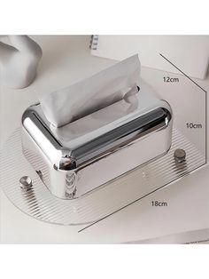 a silver tissue dispenser sitting on top of a table