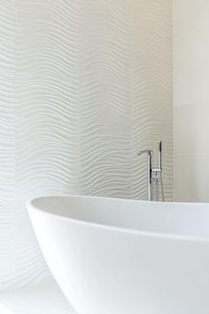 a white bath tub sitting next to a wall mounted faucet in a bathroom