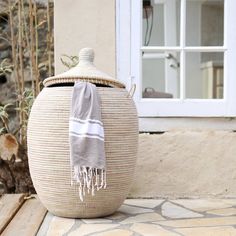 a large woven basket with a towel hanging from it's lid on a patio