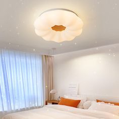 a white bed sitting under a ceiling light in a bedroom