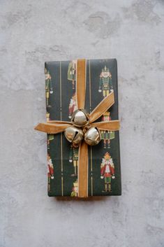 a present wrapped in green wrapping paper with bells on the top and gold ribbon tied around it