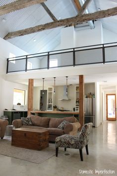 a living room filled with furniture under a wooden beam