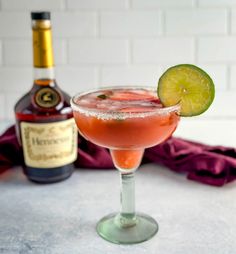 a close up of a drink in a wine glass with a lime slice on the rim