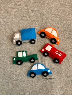 four small toy cars sitting on top of a gray t - shirt