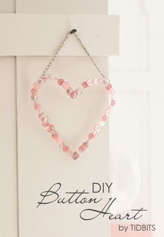 a heart shaped beaded necklace hangs on a door handle with the words button heart by tidbits