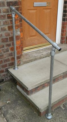 a metal hand rail sitting on the side of a door way next to a brick building