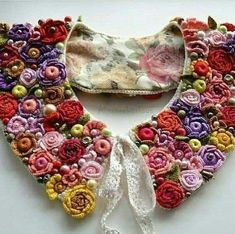 the collar is decorated with colorful flowers and pearls on it's sides, along with a white ribbon