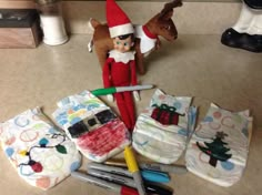 an elf is sitting on the floor next to some wrapping paper and scissors with other items in front of him