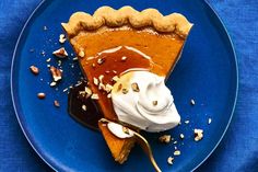 a slice of pumpkin pie on a blue plate with whipped cream and walnut toppings