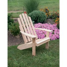 a wooden chair sitting on top of a lush green field next to purple and yellow flowers