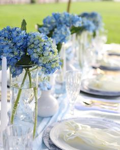 the table is set with blue flowers in vases