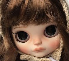 a close up of a doll wearing a hat and scarf