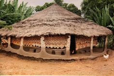 a small hut with thatched roof in the middle of some trees and bushes behind it