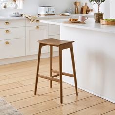 a wooden stool sitting on top of a hard wood floor next to a kitchen counter