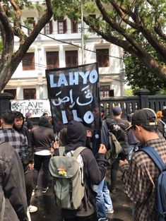 a group of people standing in front of a building holding signs that say lahayo