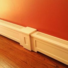 two white radiators sitting on top of a wooden floor next to a red wall