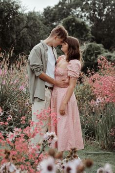 a man and woman standing next to each other in front of flowers