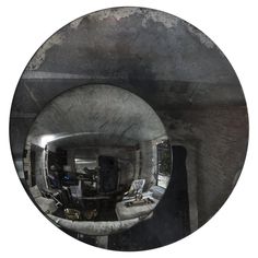 the reflection of a person in a round mirror on a white wall with grey and black paint