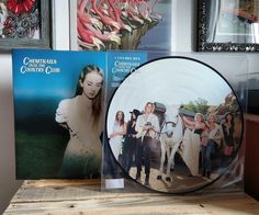 two cds sitting on top of a wooden table next to framed pictures and other items