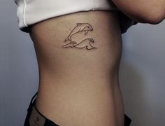 a woman's stomach with a dolphin tattoo on her side and the bottom part of her body