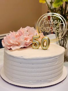 a white cake with pink flowers and a happy birthday sign on it's side