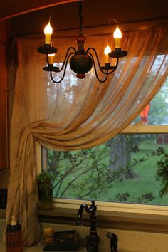 a kitchen window with curtains and lights hanging from it's valance over the sink